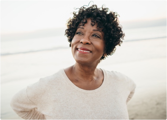 Stock photo of an older woman smiling at the beach.